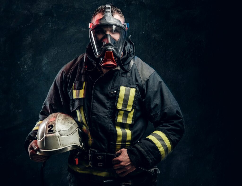 Portrait of a male in full firefighter equipment posing in a dark studio