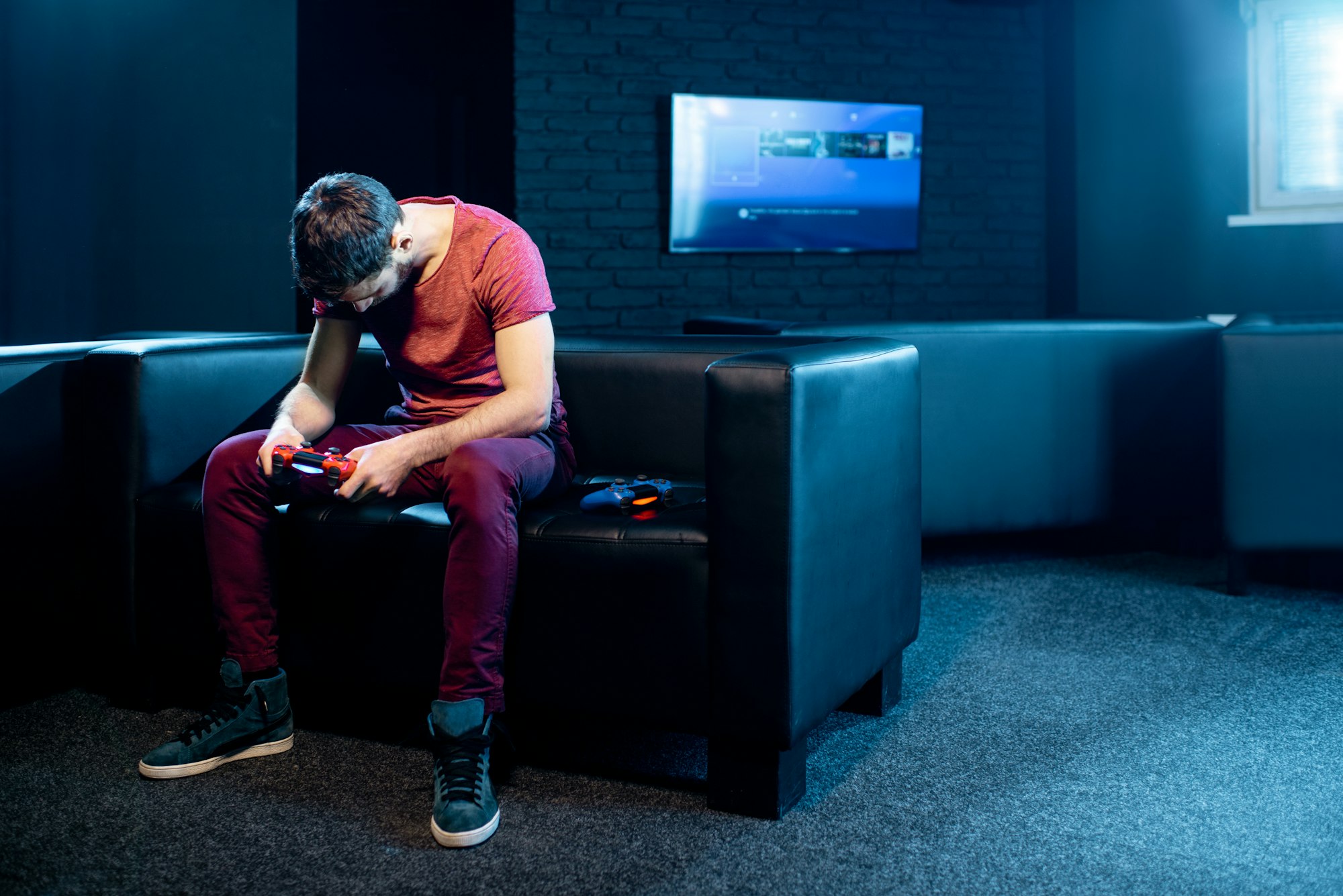 Sad man playing video games with gaming console in the club